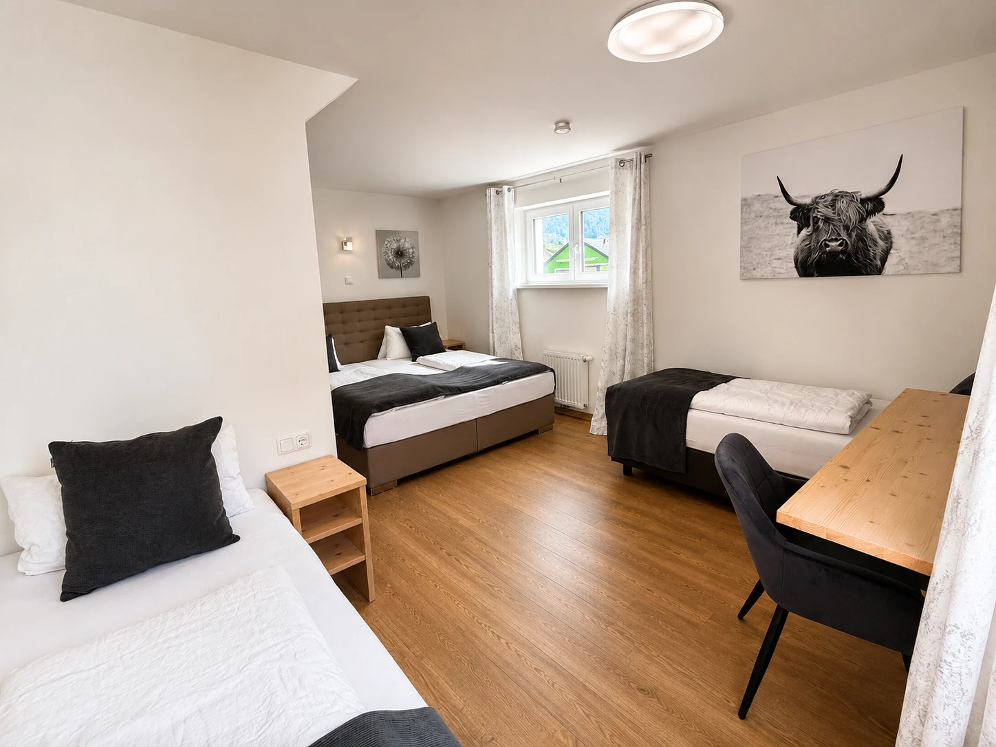 Zimmer mit grüner Filzwand, Holzbett und gemütlicher Couch